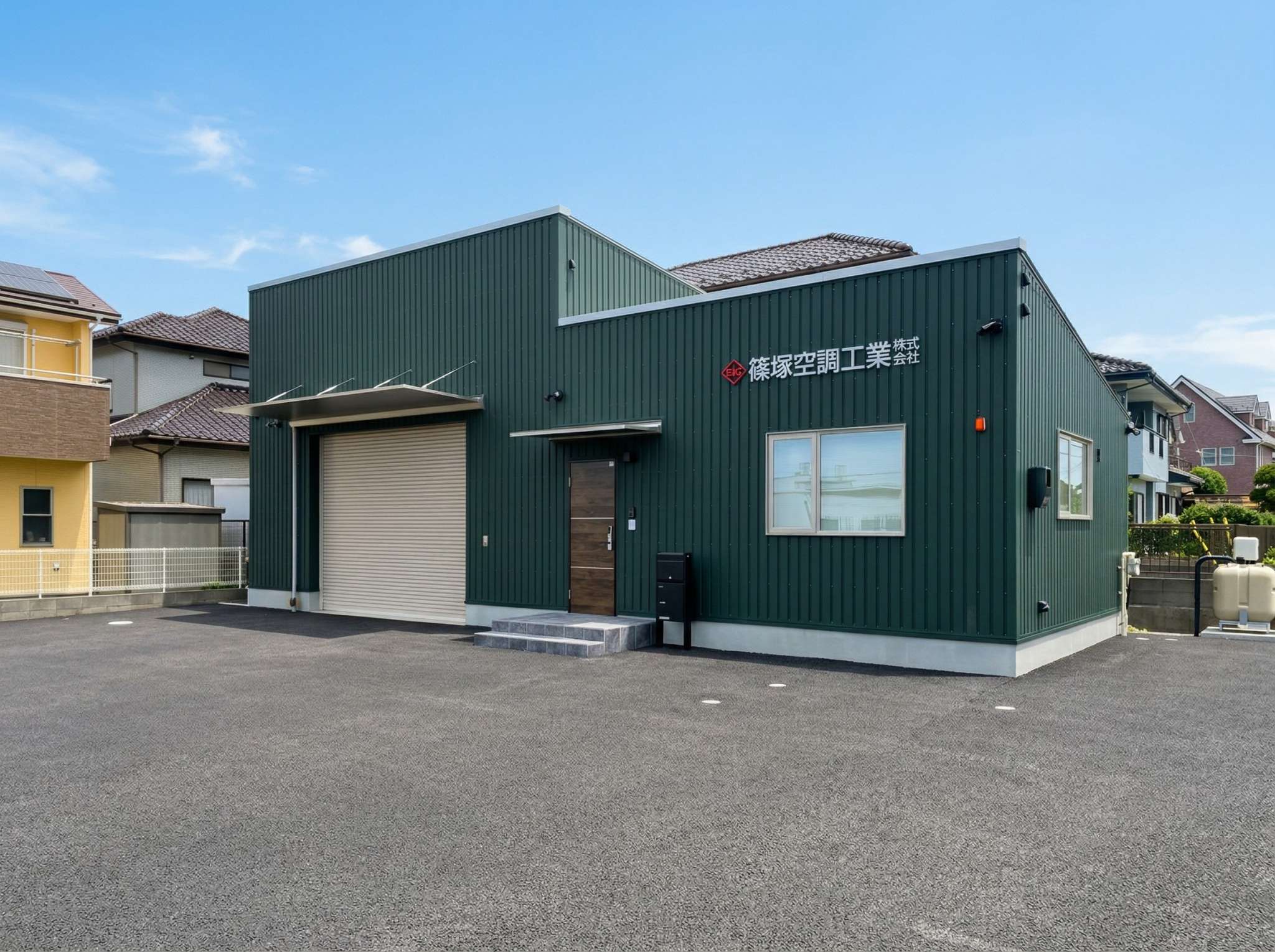 大きなシャッター開口と木目玄関ドアを備えた八街市の事務所・倉庫